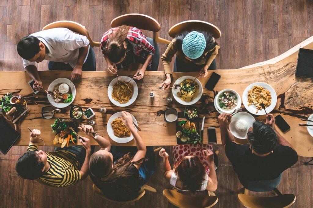 Family sitting at a wooden table eating food viewed from above